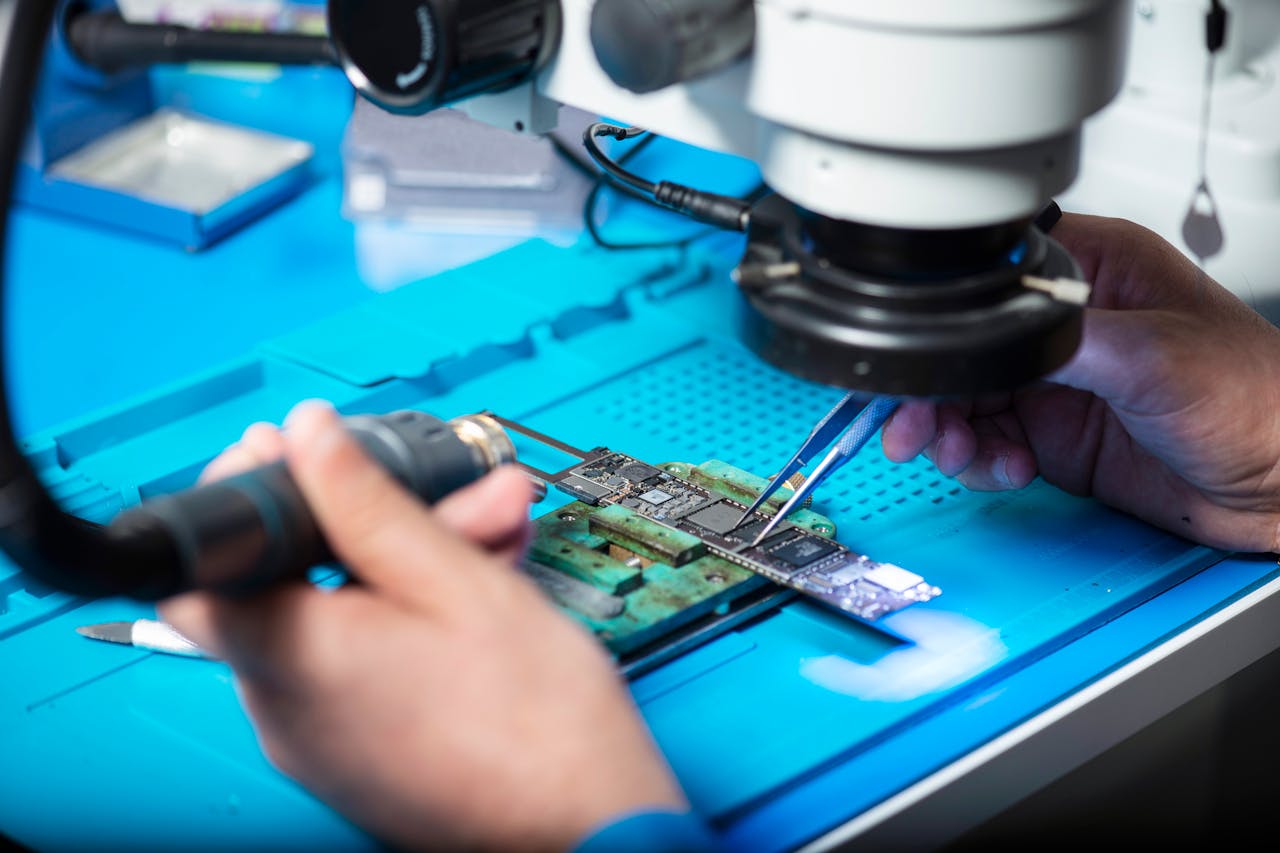team-01 Close-up of technician repairing electronic circuit board under a microscope in Toronto lab.